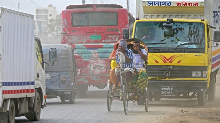 Two men in road traffic cover their nose amidst polluted air