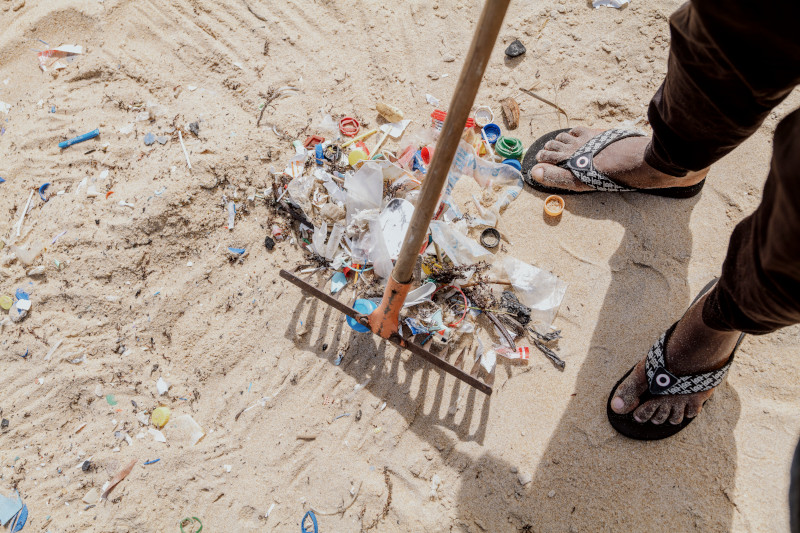 A man cleans plastic from a beach in the Republic of Côte d’Ivoire 