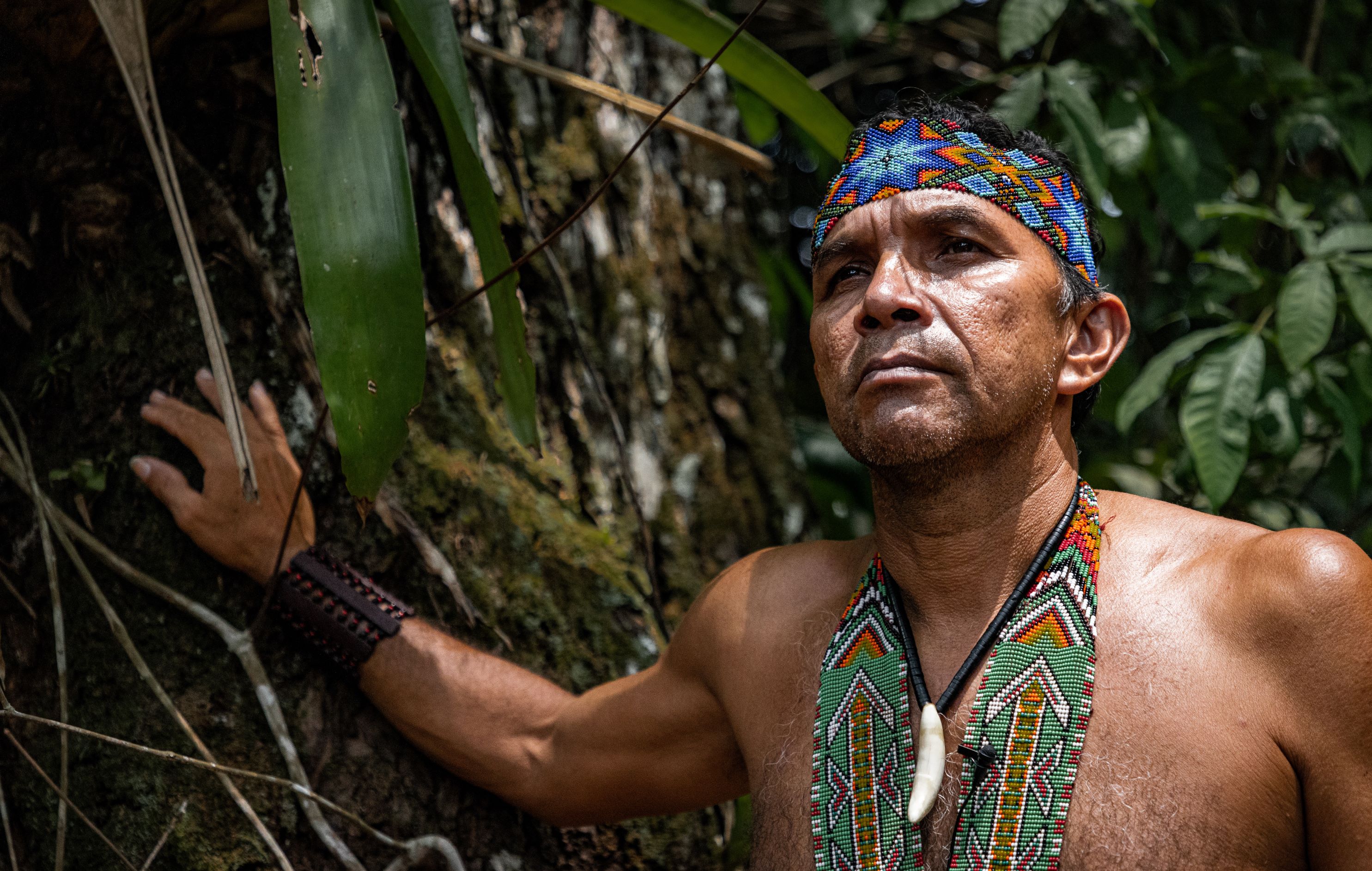 A man in traditional dress posing in front of a tree 