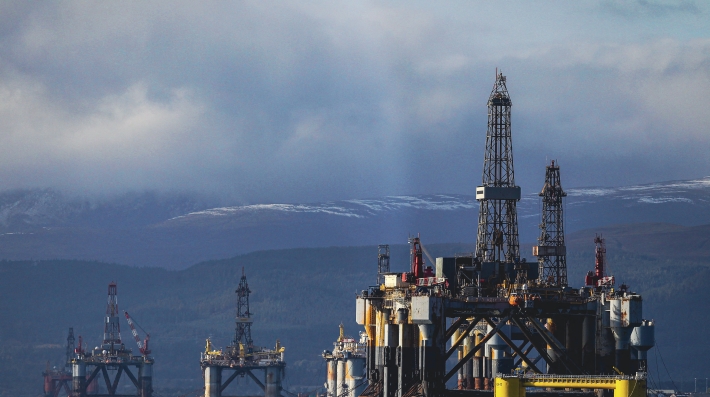 A series of oil derricks with dark clouds looking overhead