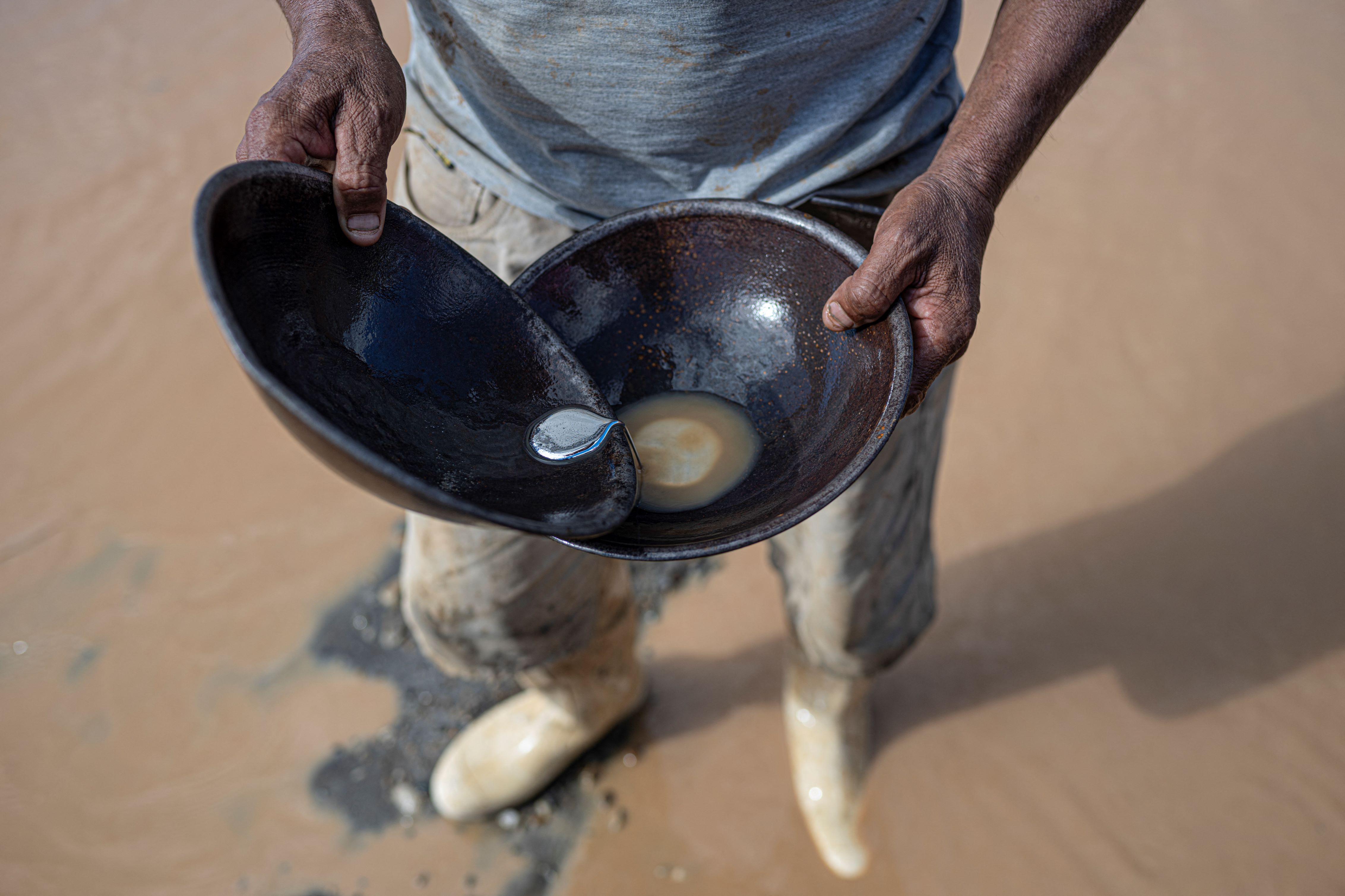 A man holding two pans with metals in them.